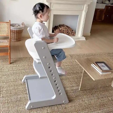 bébé fille assise dans sa chaise haute dans le salon
