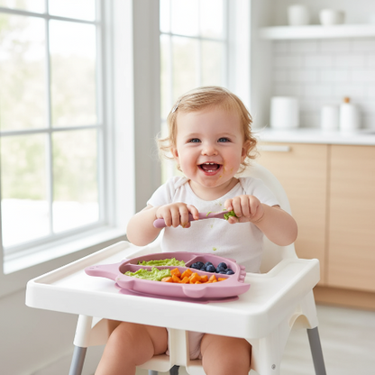 Bébé fille mangeant dans l'assiette dinosaure rose