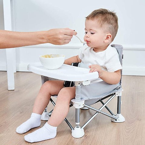 bébé assis dans une chaise au sol et mange son repas
